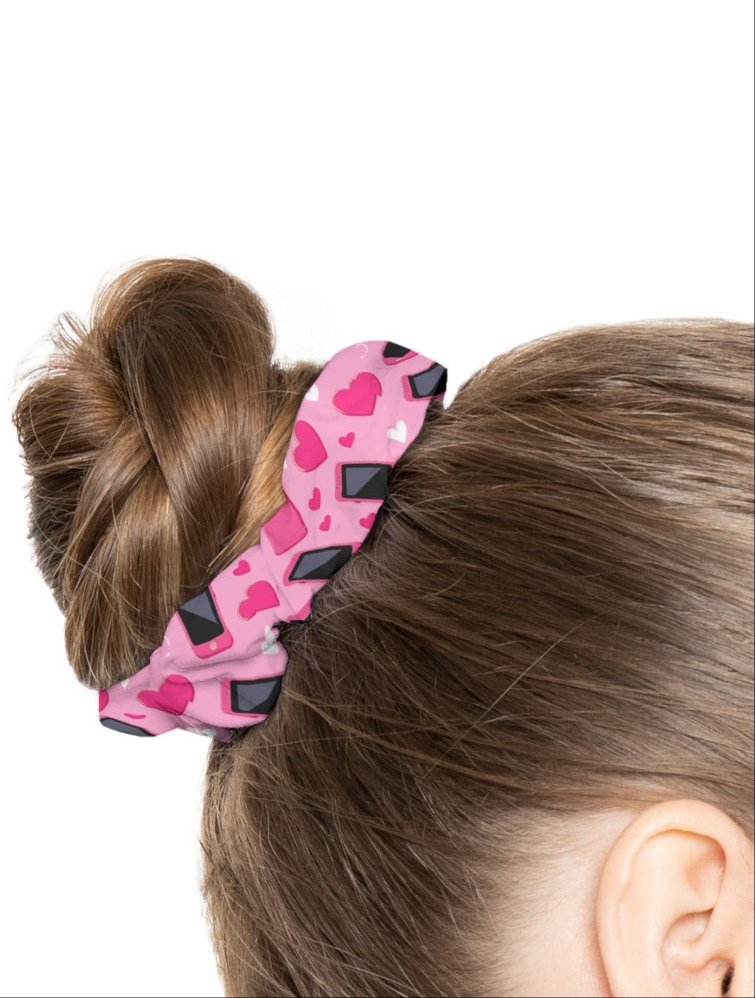 Pink hair tie with black diamond pattern on a bun, worn by a person with brown hair.